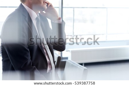 Side view of mature businessman talking on mobile phone at office