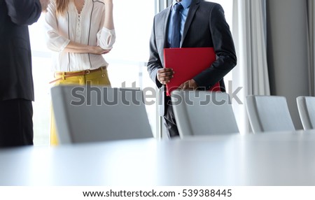 Business people having discussion while standing by conference table in office