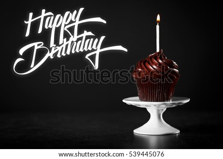 Cupcake with candle and text HAPPY BIRTHDAY on black background