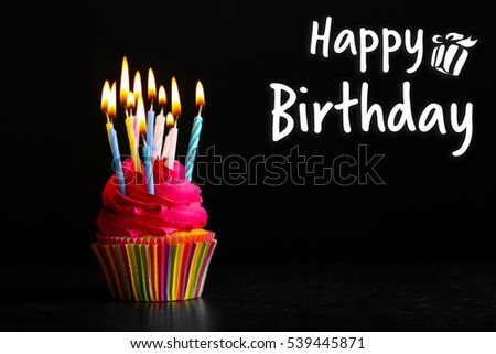 Cupcake with candles and text HAPPY BIRTHDAY on black background