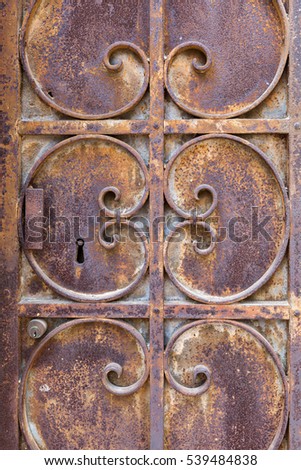 detail picture of an old ornated and rusted metal door