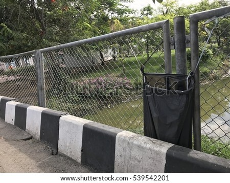 trash bags black color for Garbage tied at fence public park edge pond