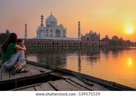 Woman watching sunset over Taj Mahal from a boat, Agra, India. It was build in 1632 by Emperor Shah Jahan as a memorial for his second wife Mumtaz Mahal. Royalty-Free Stock Photo #539571559