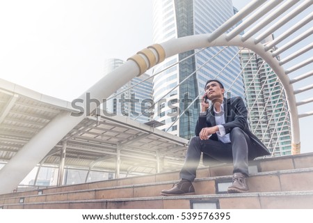 The businessman sitting on stairs and talking on smartphone