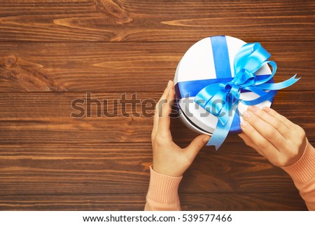 Female hands holding gift box, on wooden background