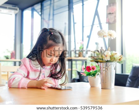 Portrait of Asia pretty little girl play mobile phone