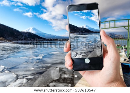 Use smart phones take photo with one hand at mount fuji in winter background