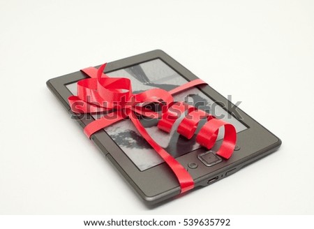 E-reader wrapped as christmas gift in red curling ribbon on a white background