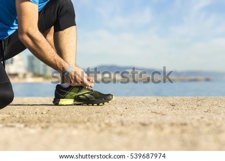 Runner tying shoelaces near the beach. Getting ready to run.