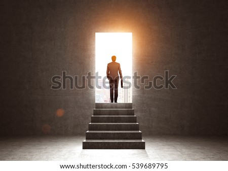 Rear view of a businessman with a suitcase exiting through a doorway in a dark concrete room into a large city. Concept of a fresh start. Toned image. Mock up Royalty-Free Stock Photo #539689795