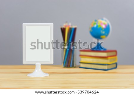 A big blank frame on the shelf, stacked books ,colored pencils and globe on the school desk,knowledge background education concept,with empty space,selective focus