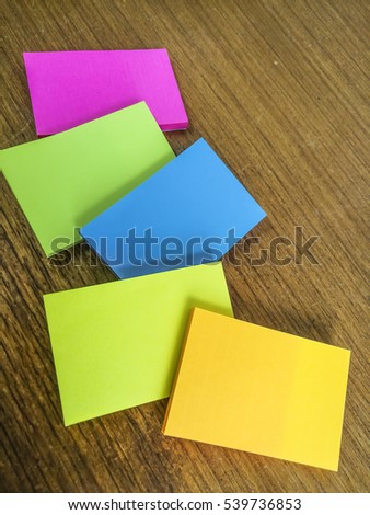 Colourful sticky notes on wooden background (Note: Image contains visible noise and blurry due to selective focusing, high iso and macro mode).