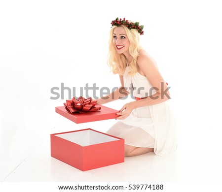 Full length portrait of a pretty young model wearing a white dress and festive flower crown. seated pose, isolated against a white studio background.