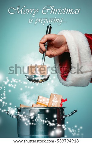 The Santa hand holding a ladle or kitchen spoon and ready for Christmas time on blue studio background. Collage and conceptual image
