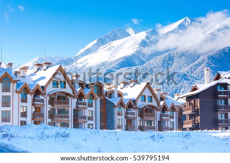 Wooden chalet, houses and snow mountains landscape panorama in bulgarian ski resort Bansko, Bulgaria Royalty-Free Stock Photo #539795194