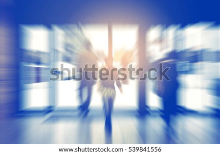blurred shopping center entrance with moving consumers in backlit