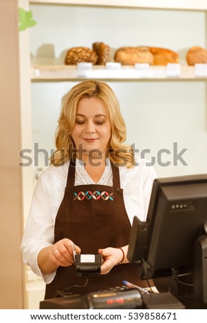 No cash payment. Vertical shot of a beautiful senior female small business owner swiping a credit card of her customer at the checkout counter of her bakery store