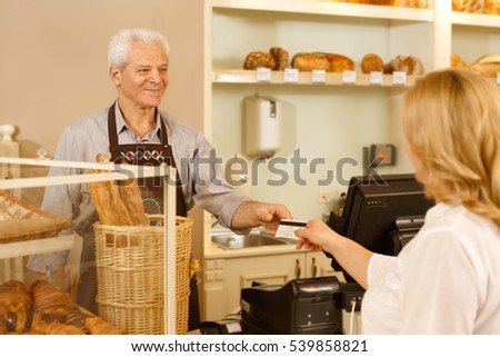 Shopping with a card. Shot of a woman paying for her purchase with a credit card at the local bakery senior baker swiping a credit card of his client shopping and consumerism concept