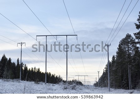 Three parallel high-voltage lines against a cloudy sky , picture from the Northern Sweden.