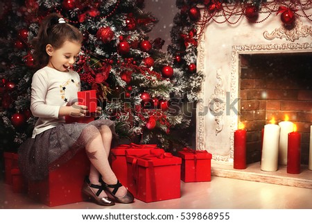 Magic gift box and a child baby girl, Christmas miracle, little beautiful happy smiling child girl opens a box with gifts. Christmas tree. New Year. Holiday and fun. 