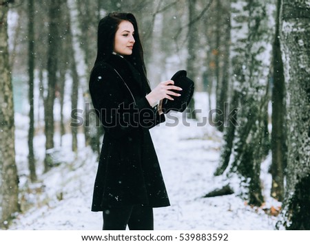 Woman winter snow nature portrait in black coat and hat
