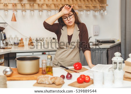 pretty young housewife in the kitchen is tired cooking tomato soup. Royalty-Free Stock Photo #539889544