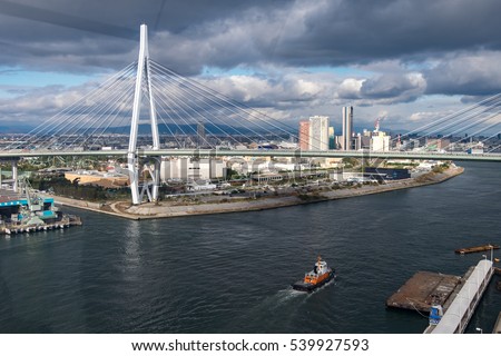 Picture from drone View of  Osaka city with Cargo ship sailing under the bridge
Japan Import and export concept