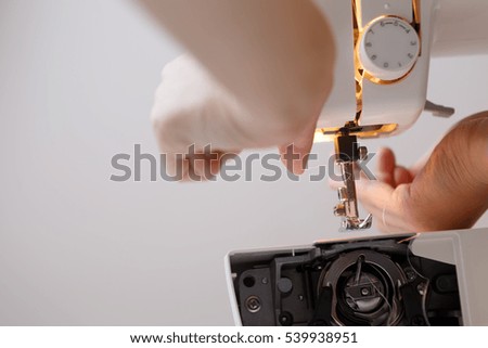 Woman inserts thread in sewing-machine