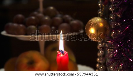 Burning Christmas candle on the background of tinsel and toys