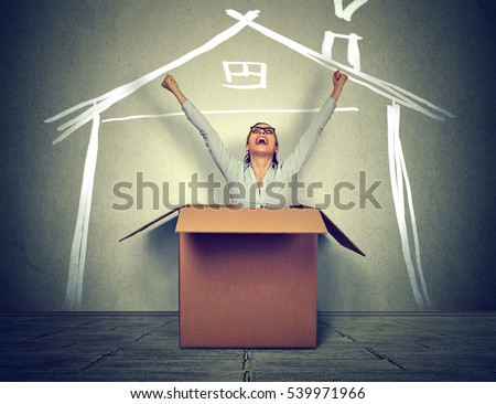 Happy woman coming out of box into a new house. Real estate concept 