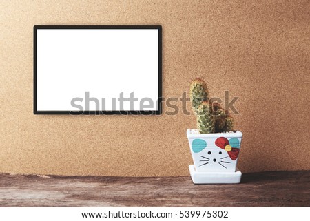 Blank white frame mockup with cactus in ceramic pot on wooden table on vintage tone. Poster product design styled mock-up.