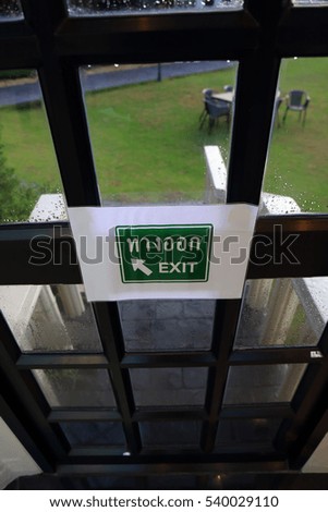 Exit sign on the window door with blur yard background outside