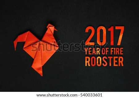 Red fire paper folded rooster handmade origami craft on black background. Nice natural holiday greeting card. 2017 year of fire rooster text lettering.