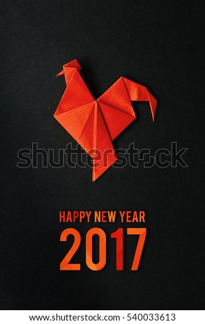 Red fire paper folded rooster handmade origami craft on black background. Nice natural holiday greeting card. Happy new year 2017 lettering,