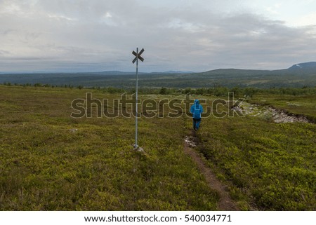 Man in blue jacket and pants hiking along the path