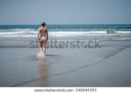 curvy blonde girl in a swimsuit walks into the ocean