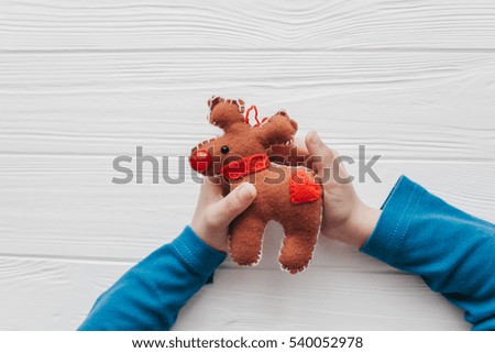 child holding a Christmas felt toy on a white wooden background Royalty-Free Stock Photo #540052978