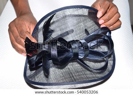 Female holding a navy blue royal ascot hat with a large bow
