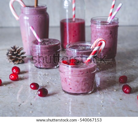 Juicy berry fruit smoothies in glass, jars, bottles on marble background. Christmas cranberry theme. Selective focus. Toning.