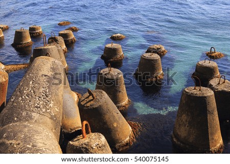 Huge stone anchors near the beach in the blue sea