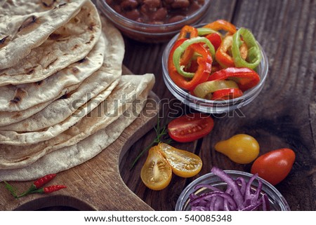 Mexican corn tortilla tacos with vegetables on wooden background