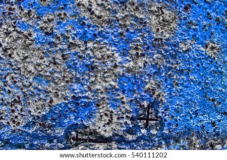 Fragment of  old grungy texture with chipped paint and cracks or blue grey concrete wall and cement surface with small stones and metallic elements, dirty 