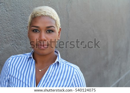 Beautiful young African American woman with short dyed blond hair looking at camera with a relaxed neutral expression
