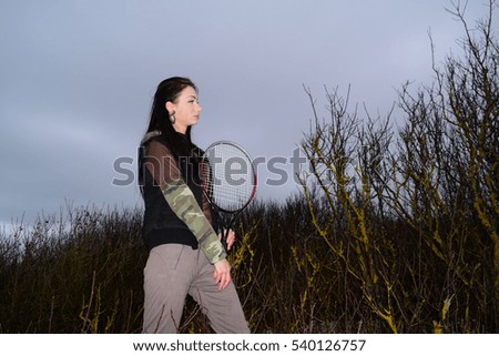 Beautiful girl in a tracksuit with a tennis racket on the sea background