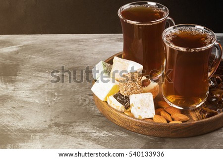 Black tea, oriental sweets, dates and nuts on a dark background. Copy space. Food background. Toning