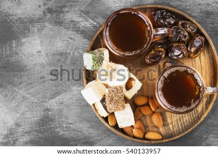 Black tea, oriental sweets, dates and nuts on a dark background. Top view, copy space. Food background