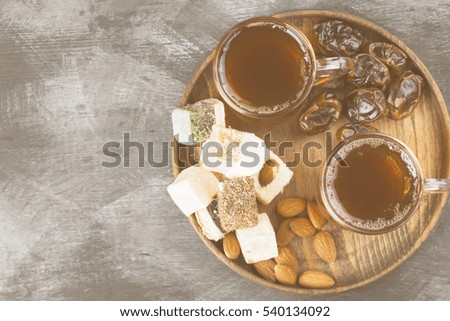 Black tea, oriental sweets, dates and nuts on a dark background. Top view, copy space. Food background. Toning