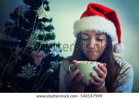 Portrait of happy teenager girl in santa hat with cup of hot chocolate