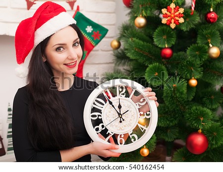 cute girl in santa hat with decorated christmas tree and old clock