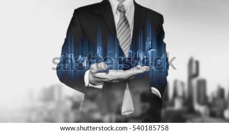 Businessman holding blue modern buildings hologram on hand, with black and white city background Royalty-Free Stock Photo #540185758